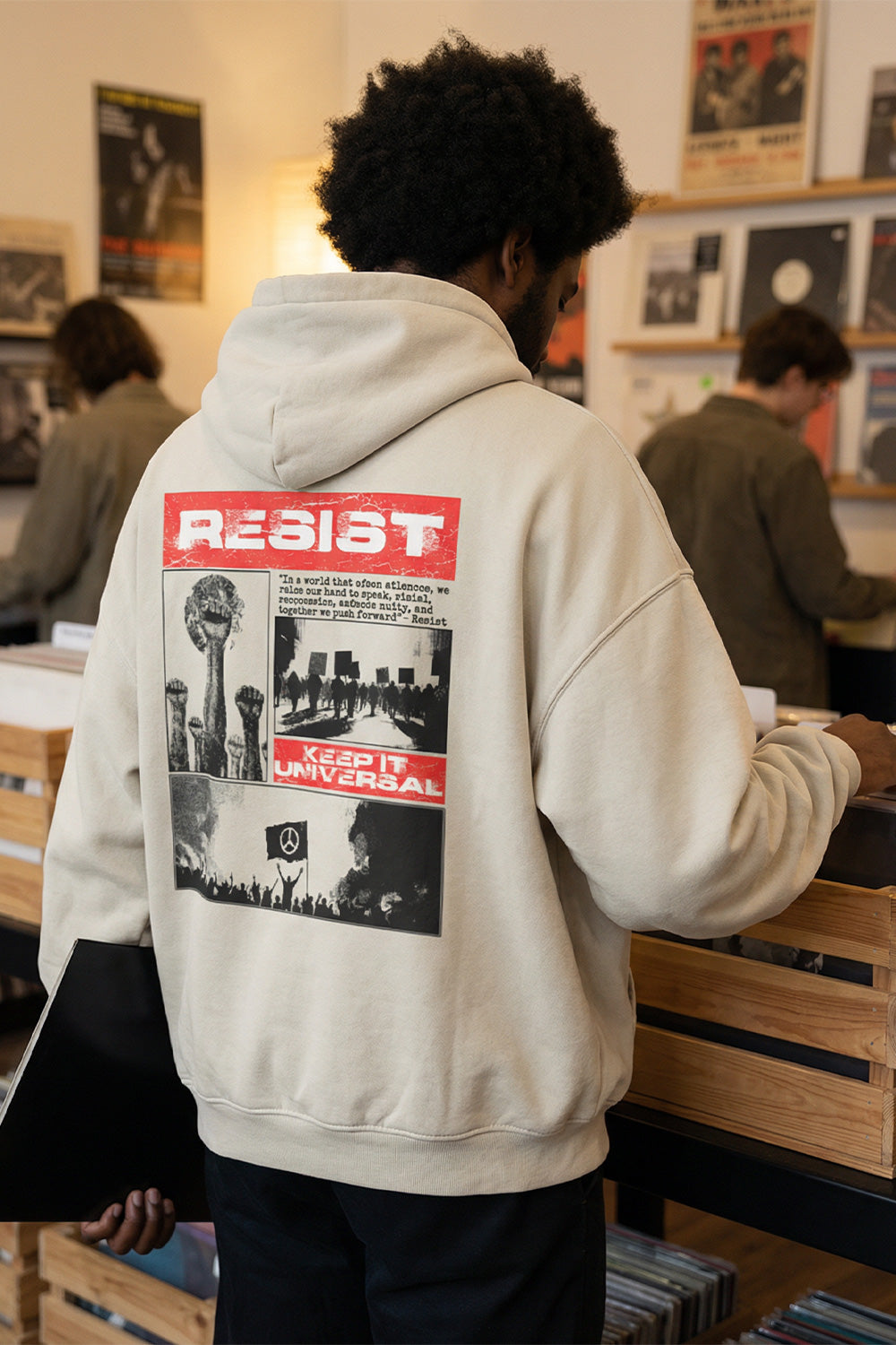 Person wearing a graphic streetwear hoodie while browsing records in a music store.